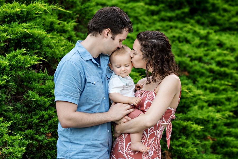 Two parents kiss their baby boy at Scott Arboretum on the Swarthmore College campus.